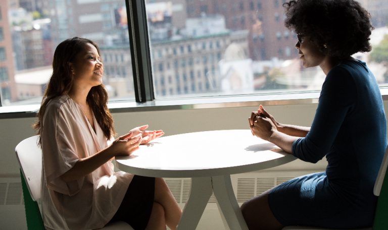 Two business owners meeting at a small table by an office window
