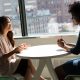 Two business owners meeting at a small table by an office window