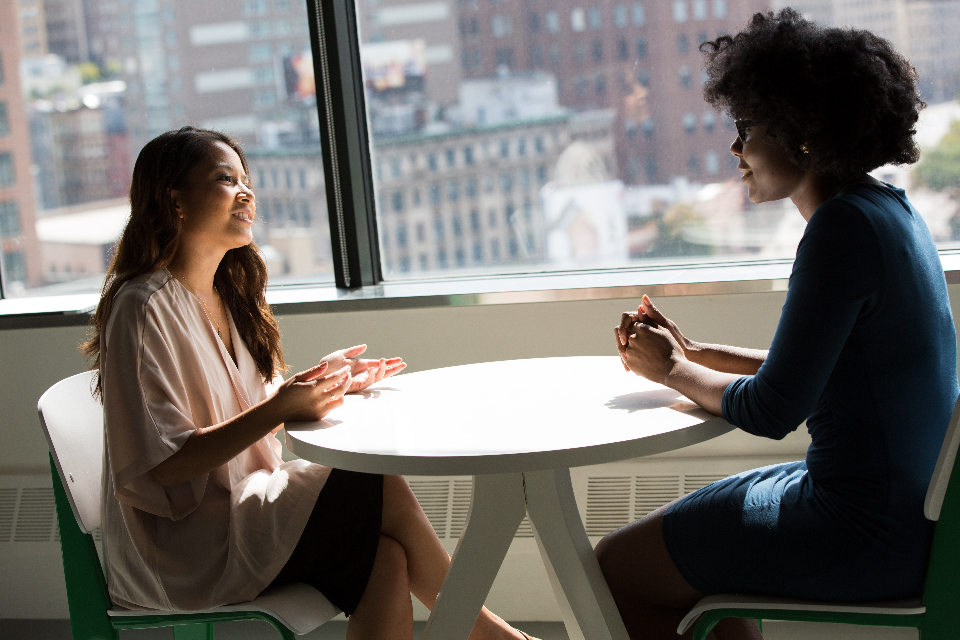 Two business owners meeting at a small table by an office window